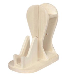 May include: A wooden stand with two slots for holding headphones and a shelf for storing other items. The stand is made of unfinished wood and has a natural colour.