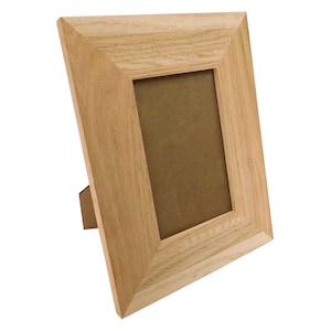 May include: A light oak picture frame with a rectangular aperture and an integrated easel back. The frame is constructed from natural wood and features a simple, classic design. The frame is angled, highlighting its depth and the neutral-toned backing.