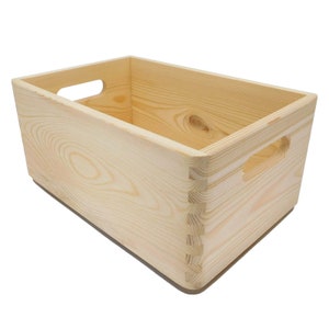 May include: A natural wood storage box with two cut-out handles on the sides. The box is made of unfinished pine wood and has a rectangular shape.