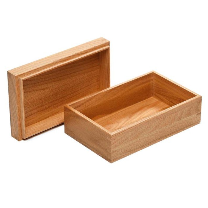 May include: A wooden box with a lid, open to reveal the empty interior. The box is made of light brown wood with a smooth finish.