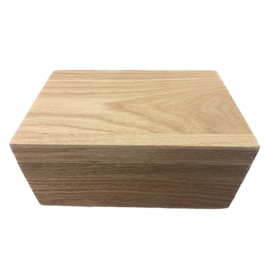 May include: A light brown wooden box with a smooth, grain-like texture. The box is closed and has a rectangular shape.