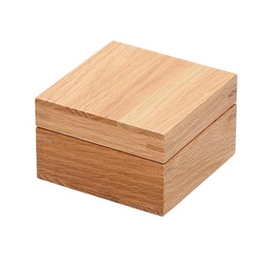 May include: A wooden box with a lid. The box is made of light brown wood and has a natural finish. The lid is slightly ajar, revealing the interior of the box.