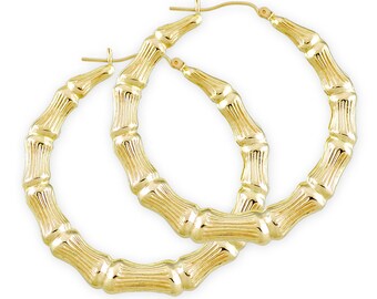 May include: A pair of gold bamboo hoop earrings. The earrings are large and have a textured surface.