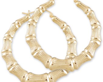May include: A pair of gold bamboo hoop earrings. The earrings are made of a thick, textured metal that resembles bamboo.