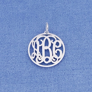 May include: Silver monogram pendant with the letters "ABC" in a circular, open-style design.