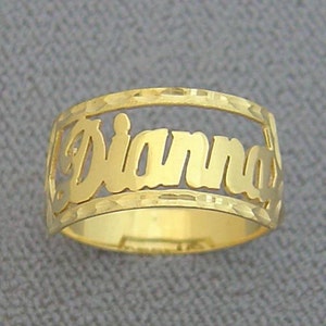 May include: Gold ring with the name "Dianna" cut out in the band. The ring has a textured finish.