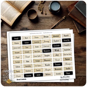 May include: A sheet of Soul Labels with various inspirational words like "Dream," "Joy," and "Peace" in a vintage style. The labels are rectangular with a cream background and black or dark brown borders. The image includes books and stationery.