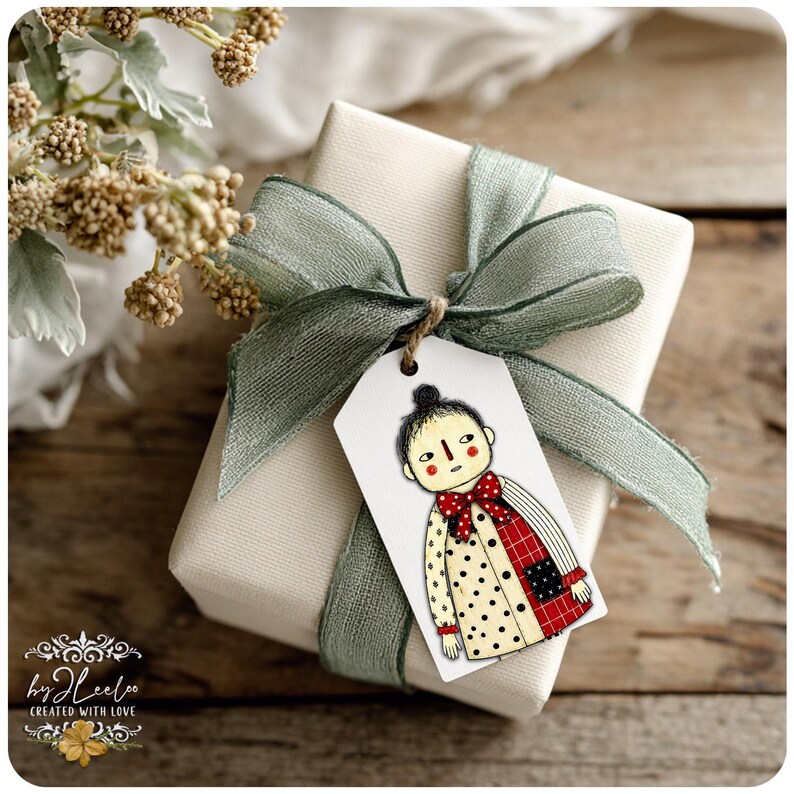 Puede incluir: Un regalo envuelto con una cinta verde salvia y una etiqueta con una ilustraci&oacute;n caprichosa de una persona con un abrigo de lunares y una pajarita roja. La etiqueta est&aacute; atada con hilo. El regalo est&aacute; sobre una superficie de madera.