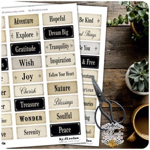 May include: Two sheets of paper with various inspirational words printed on them, including "Adventure," "Dream Big," and "Peace." The words are in a vintage style with a cream and black color scheme. A pair of scissors and a cup are also visible.