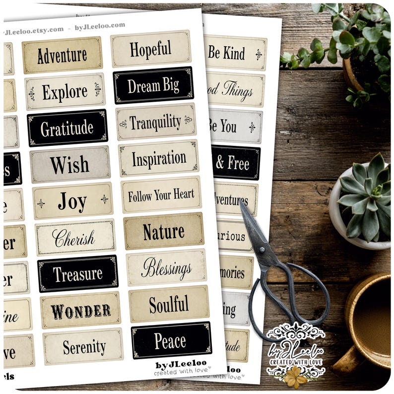 May include: Two sheets of paper with various inspirational words printed on them, including "Adventure," "Dream Big," and "Peace." The words are in a vintage style with a cream and black color scheme. A pair of scissors and a cup are also visible.