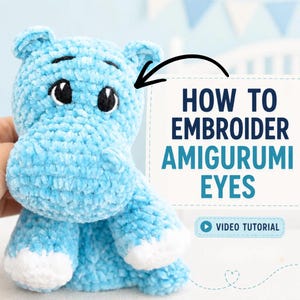 Könnte beinhalten: Ein hellblaues Plüsch-Nilpferd mit weißen Füßen und gestickten schwarzen Augen. Ein schwarzer Pfeil zeigt auf die Augen, und der Text lautet: HOW TO EMBROIDER AMIGURUMI EYES, VIDEO TUTORIAL. Das Spielzeug hat eine weiche, strukturierte Oberfläche.