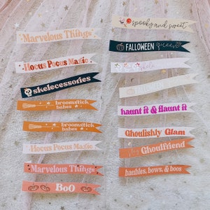 Puede incluir: Un conjunto de 12 pancartas imprimibles con tem&aacute;tica de Halloween con varios lemas espeluznantes y lindos. Las pancartas son de varios colores, incluidos el rosa, el naranja, el negro y el blanco. El texto en las pancartas incluye frases como "spooky and sweet", "haunt it & flaunt it", "broomstick babes" y "ghoulishly glam".