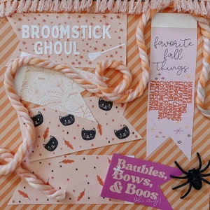 Puede incluir: Un conjunto de cinco pancartas imprimibles con tem&aacute;tica de Halloween con fondos naranja y rosa. Las pancartas presentan gatos negros, estrellas y texto que dice "Broomstick Ghoul", "Cosas favoritas del oto&ntilde;o" y "Adornos, lazos y &iexcl;Bu! &iexcl;Oh, Dios m&iacute;o!"
