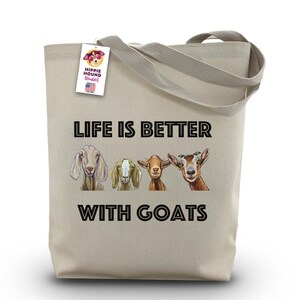 Può includere: Una borsa tote in tela beige con la scritta "LIFE IS BETTER WITH GOATS" e illustrazioni di quattro capre. La borsa ha un'etichetta con la scritta "Hippie Hound Studios" e "Made in the USA".