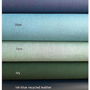 May include: Five stacked rolls of material featuring distinct colors and textures. The top roll is labeled Peacock, followed by Skye, Fern, and Ivy, all showing a fine-grained surface. The bottom roll is labeled Ink-blue recycled leather.