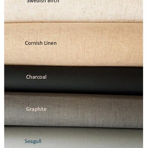 May include: Five stacked rolls of fabric in varying neutral tones. The top roll is labeled Swedish Birch, followed by Cornish Linen, Charcoal, Graphite, and Seagull. Each roll displays a distinct texture and color, ranging from off-white to light gray.