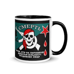 May include: White ceramic mug with a black interior and handle. The mug features a design with a skull wearing a red bandana, a red star, and text in a foreign language. The design is set against a teal and black background.