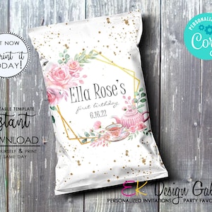 May include: A white chip bag with a gold geometric frame and pink floral design. The text "Ella Rose's first birthday 6.16.22" is printed on the bag.