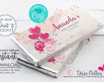 May include: Personalized chocolate bar wrapper with a pink and gold watercolor background. The wrapper features a floral design with pink roses and hearts. The text "Amanda's First Birthday 2-14-2022" is printed on the wrapper. The wrapper fits a 1.55 oz chocolate bar.