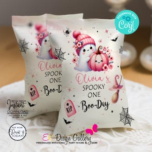 May include: Two white treat bags with a Halloween theme. Each bag features a cartoon ghost wearing a pink hat, a pink pumpkin, and the text "Olivia Spook One Boo-Day". The bags are decorated with spiders, bats, and flowers.