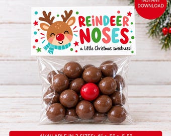 May include: A clear plastic bag filled with round brown chocolate candies and one bright red candy. The bag has a white header card featuring a cartoon reindeer, colorful stars, and the text REINDEER NOSES a little Christmas sweetness.