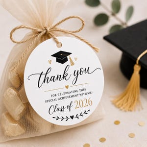 May include: A graduation-themed gift bag with a round tag that says "Thank you" and "Class of 2026." The tag features a graduation cap graphic and is tied to the bag with twine. The bag is filled with small, gold-wrapped candies.