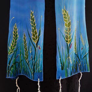 May include: Two blue fabric panels with a wheat field design. The wheat is green and gold, with green grass and purple accents. White tassels hang from the bottom of each panel.
