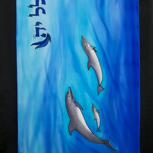May include: A blue and white silk tallit with Hebrew text and a design of three dolphins swimming in the ocean.