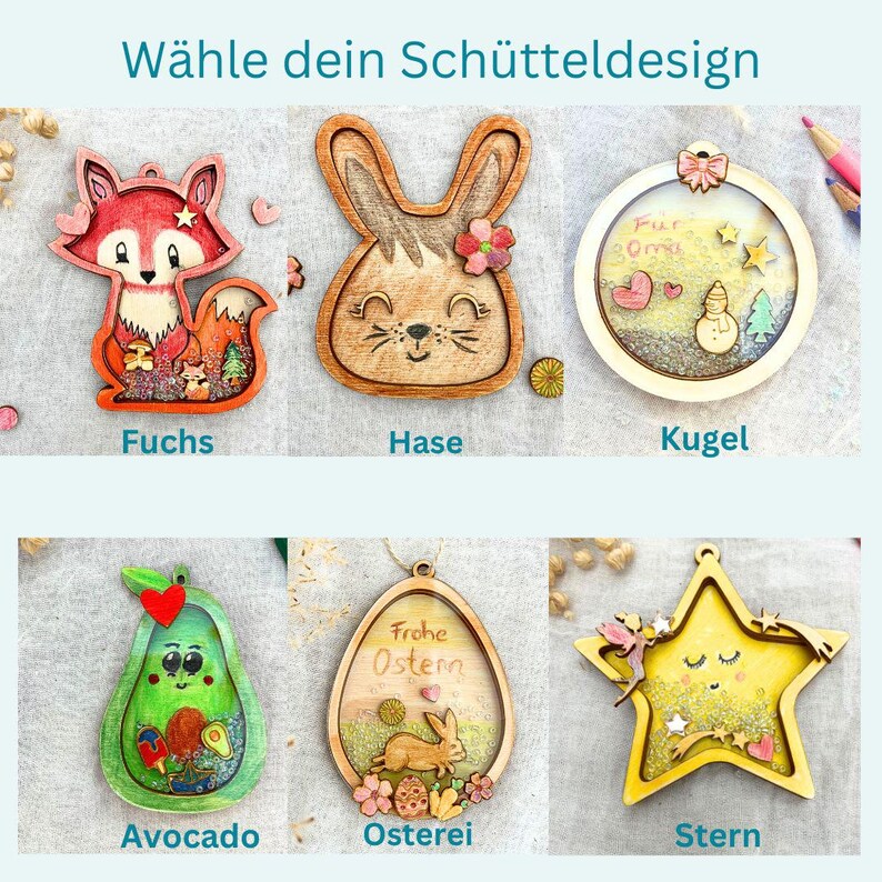May include: A collection of wooden ornaments in various shapes, including a fox, bunny, avocado, and star. Each ornament features intricate details and vibrant colors, with some containing small decorative elements. The text "W&auml;hle dein Sch&uuml;tteldesign" is at the top.