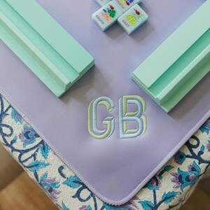 a collection of colorful tiles and a purple mat with the initials "GB" embroidered on it.