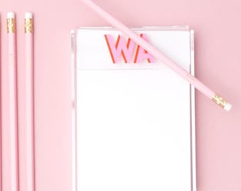 May include: A pink and white travel themed gift set with personalised luggage tags, a passport holder, a notepad, pencils, and a card holder. The luggage tags say "AW" and "KB". The notepad says "WA".