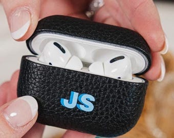 May include: Black leather Airpods case with the initials "JS" in blue lettering.