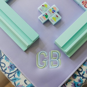a collection of colorful tiles and a purple mat with the initials "GB" embroidered on it.