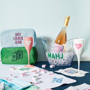 a wine bottle, wine glasses, and a green bag with text on it, all placed on a table with scattered papers and other items.