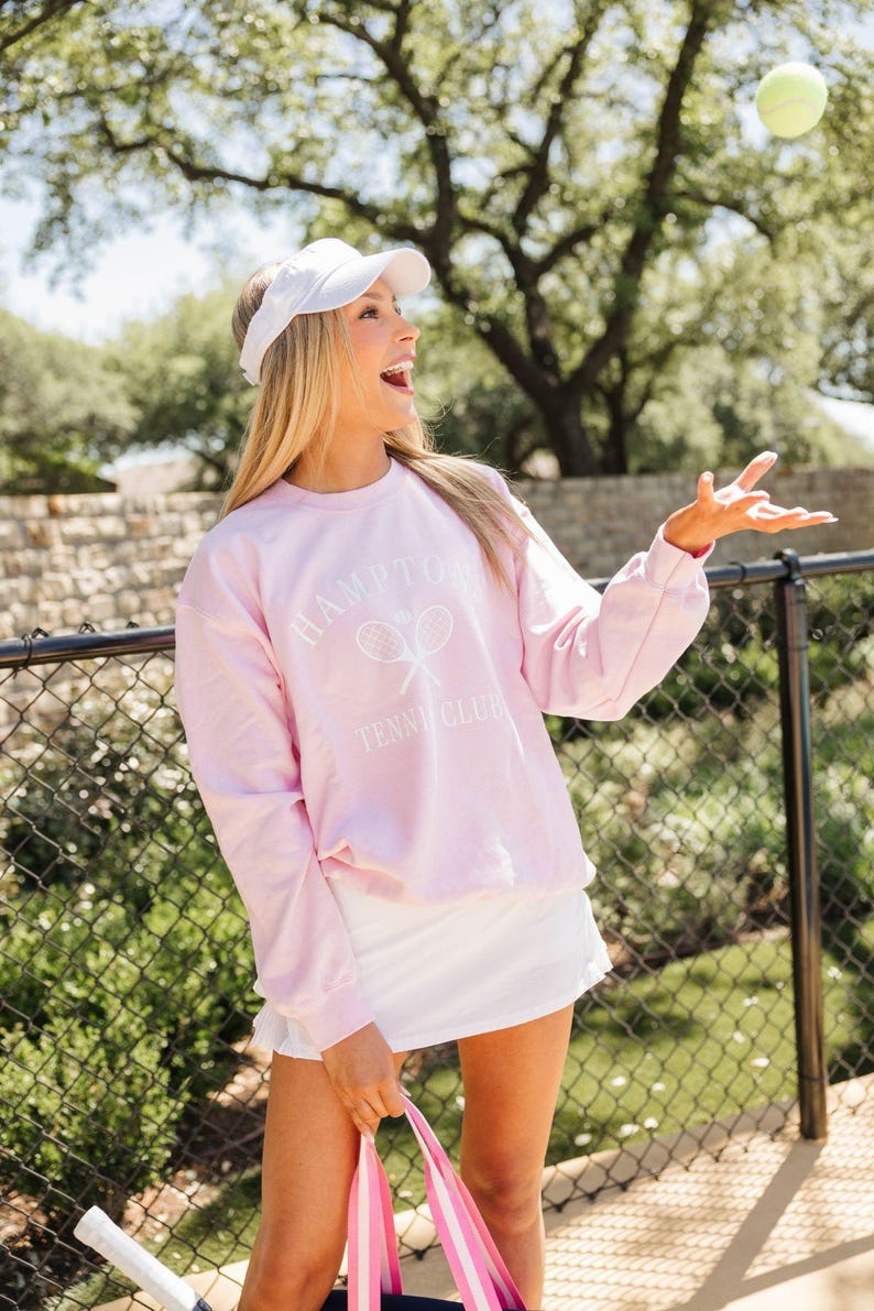 a woman in a pink sweatshirt is holding a pink bag