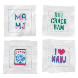 four square images, each with a different embroidered design or text. The first image features the letters "MA HJ" in a colorful, embroidered style. The second image displays the phrase "DOT CRACK BAM" in green embroidered letters. The third image shows a "JOKER" card with a joker symbol and the word "JOKER" written on it. The fourth image shows the phrase "I <3 MAHJ" in pink embroidered letters, with a heart symbol and the word "I" written below it.