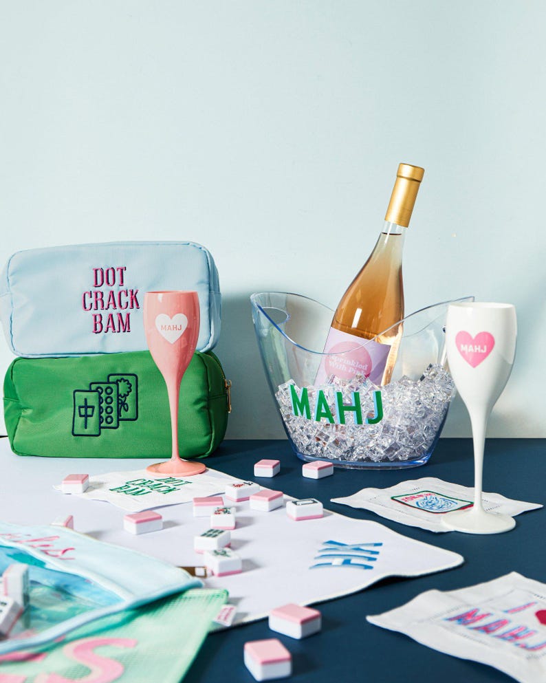 a wine bottle, wine glasses, and a green bag with text on it, all placed on a table with scattered papers and other items.