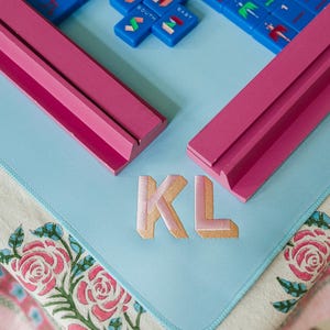 a table with a blue and pink color scheme, and there are several dominoes and a pink object with the letters "KL" on it.