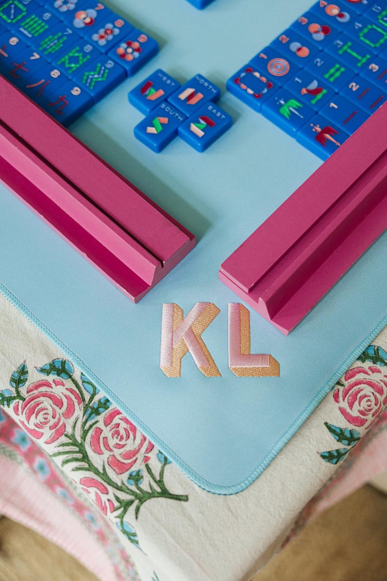 a table with a blue and pink color scheme, and there are several dominoes and a pink object with the letters "KL" on it.