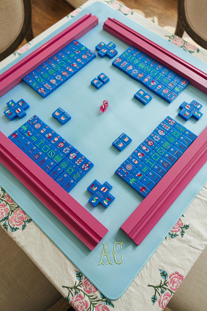 A colorful game board with blue tiles and pink pieces, arranged on a table with a floral tablecloth.