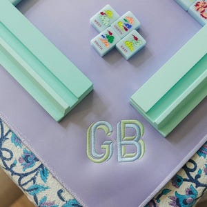 a collection of colorful tiles and a purple mat with the initials "GB" embroidered on it.