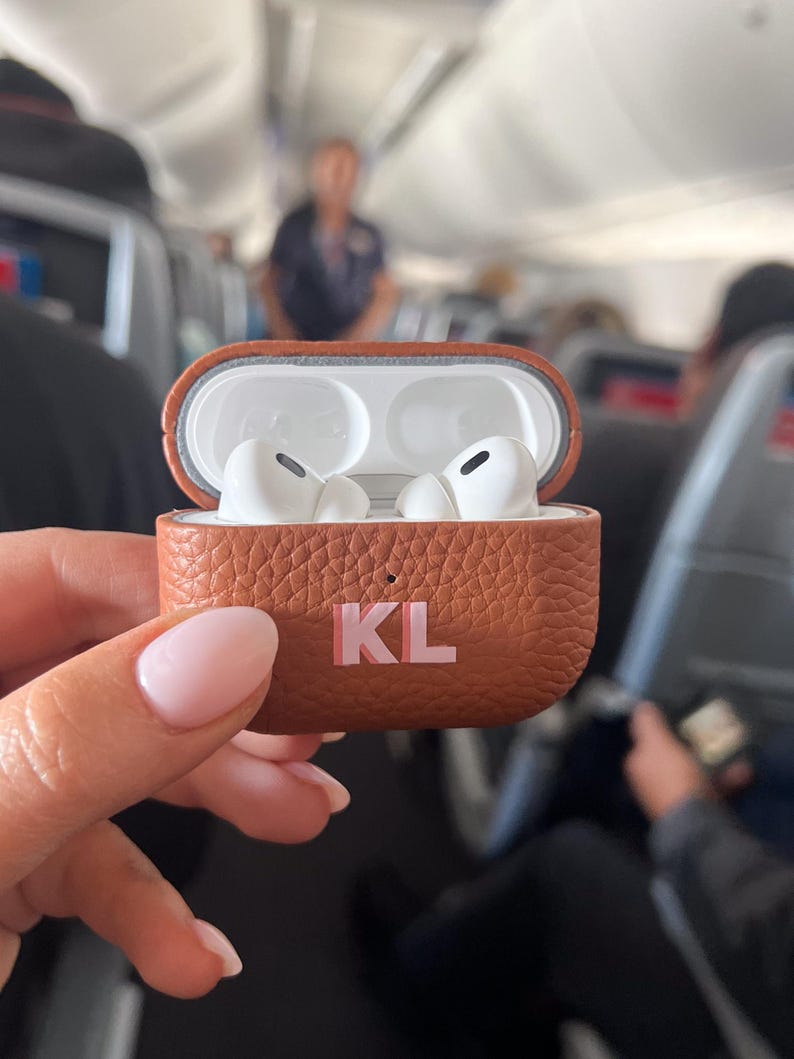 a person holding a case with two airpods in it