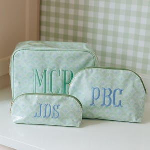May include: Three light green cosmetic bags with a repeating fan pattern and gold zippers. The largest bag features the embroidered letters MCP, the medium bag features PBG, and the smallest bag features the embroidered letters JDS in blue.
