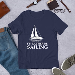 May include: A navy blue t-shirt with a white sailboat graphic and the text "I'd rather be sailing".