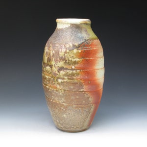 May include: A ceramic vase with a rounded body and a textured, brown, orange, and white glaze.