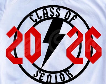 May include: A white short-sleeved t-shirt featuring a black circular graphic with the text Class of Senior and the number 2026 in red. A black lightning bolt is positioned in the center of the circle. The design is printed on the front of the shirt.