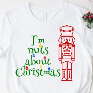 May include: White t-shirt with a green Christmas tree design and the text "I'm nuts about Christmas". A red nutcracker illustration is on the right side of the design.