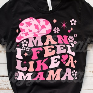 以下が含まれることがあります： ピンクの カウガールハットと「I feel like a mama」というピンクと白の文字が書かれた黒いTシャツです。