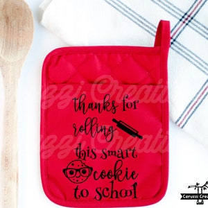 Puede incluir: Manopla de horno roja con el texto "Gracias por rodar esta galleta inteligente a la escuela" y una ilustración en blanco y negro de una galleta con gafas y un rodillo.