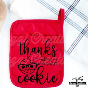 May include: Red oven mitt with a black graphic of a cookie wearing glasses and the text "thanks for making me one smart cookie".